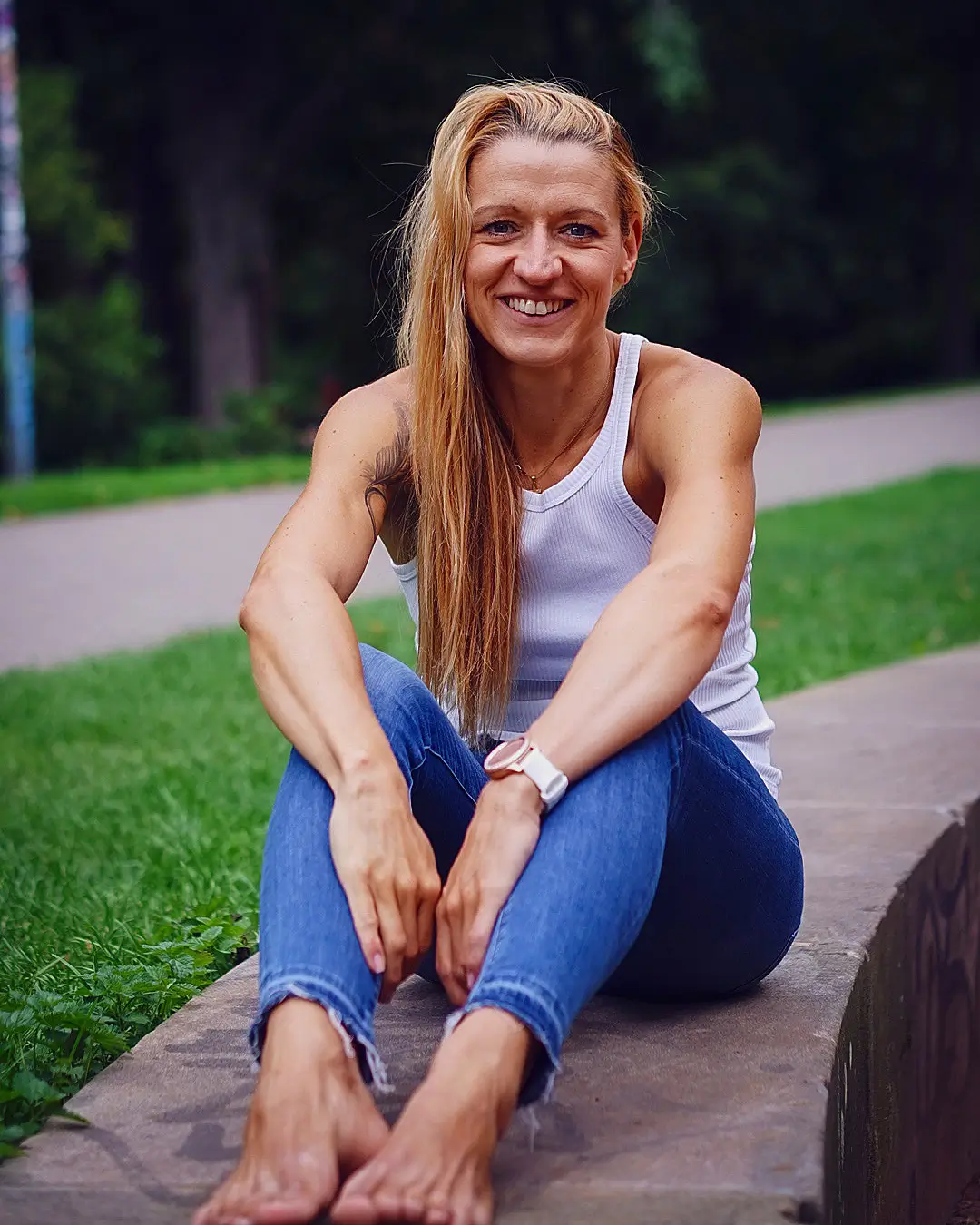 Juana Mende sitzt lachend auf einer Mauer im Park